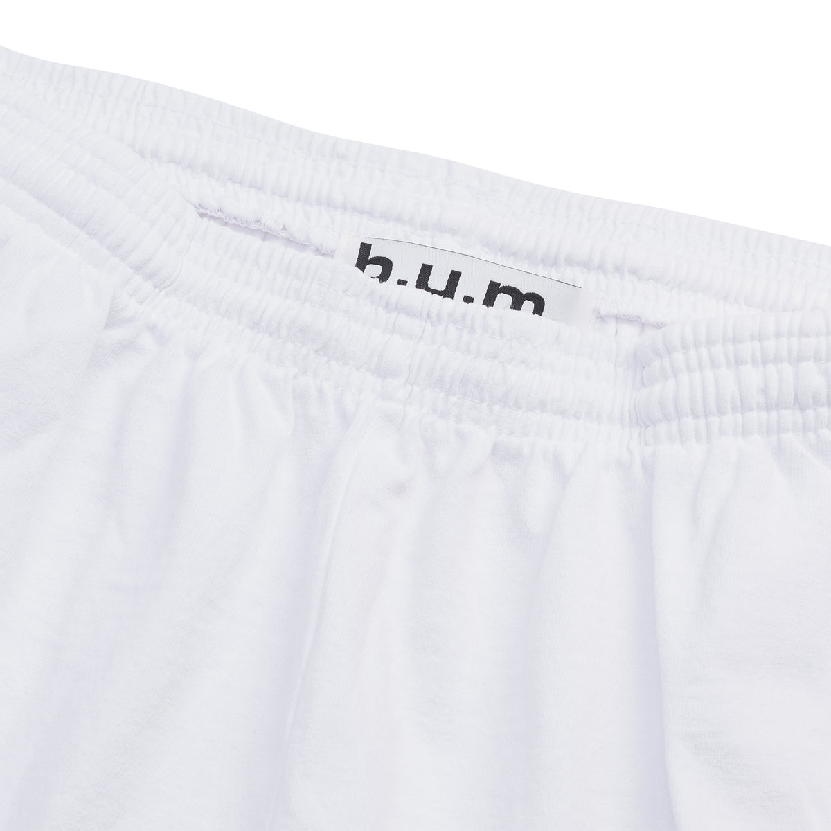 Detail of the B.U.M. Equipment white cotton shorts, showing the elastic drawstring waistband