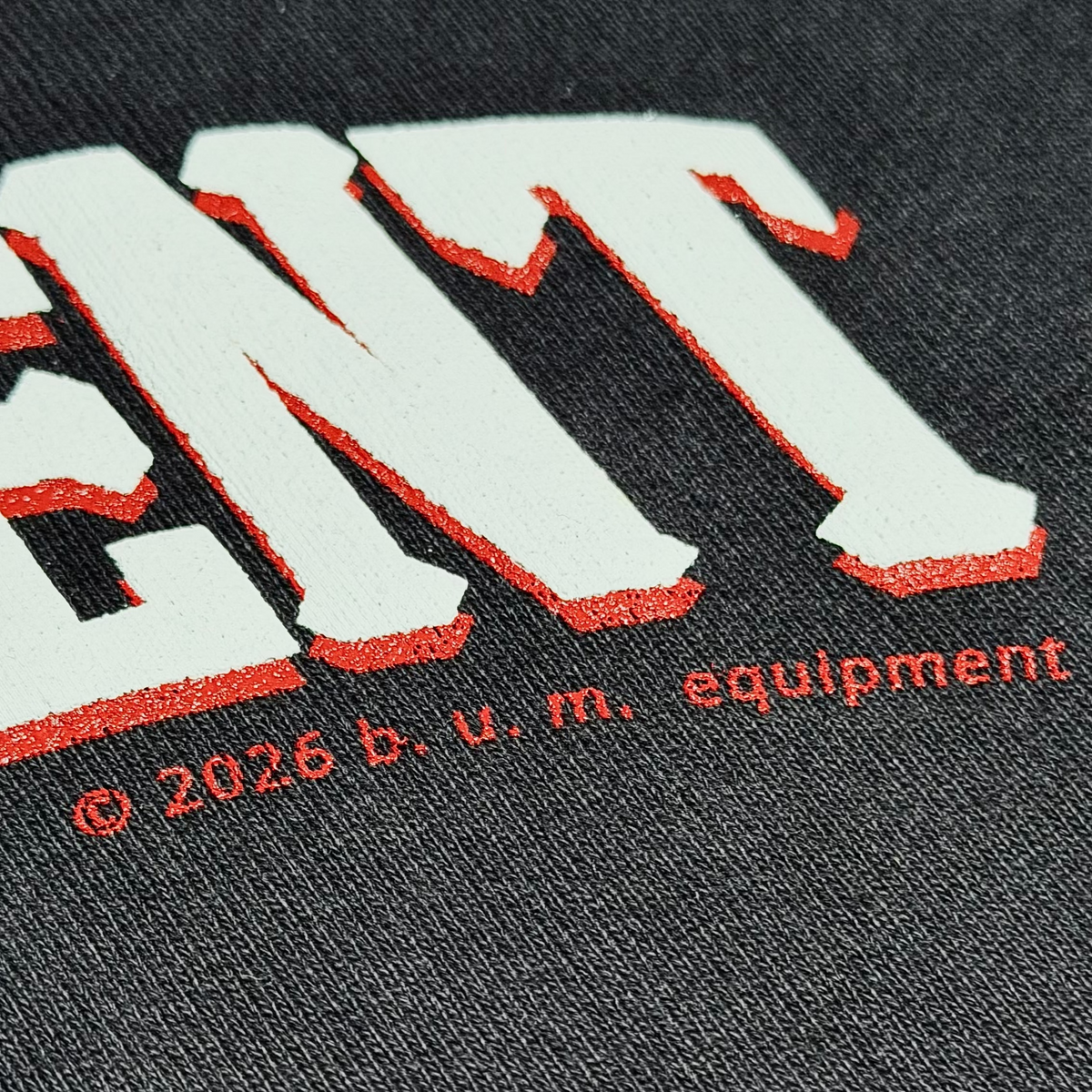 Close-up of the raised white and red B.U.M. EQUIPMENT lettering on the back of the hoodie, with the 2026 b.u.m. equipment credit printed beneath it